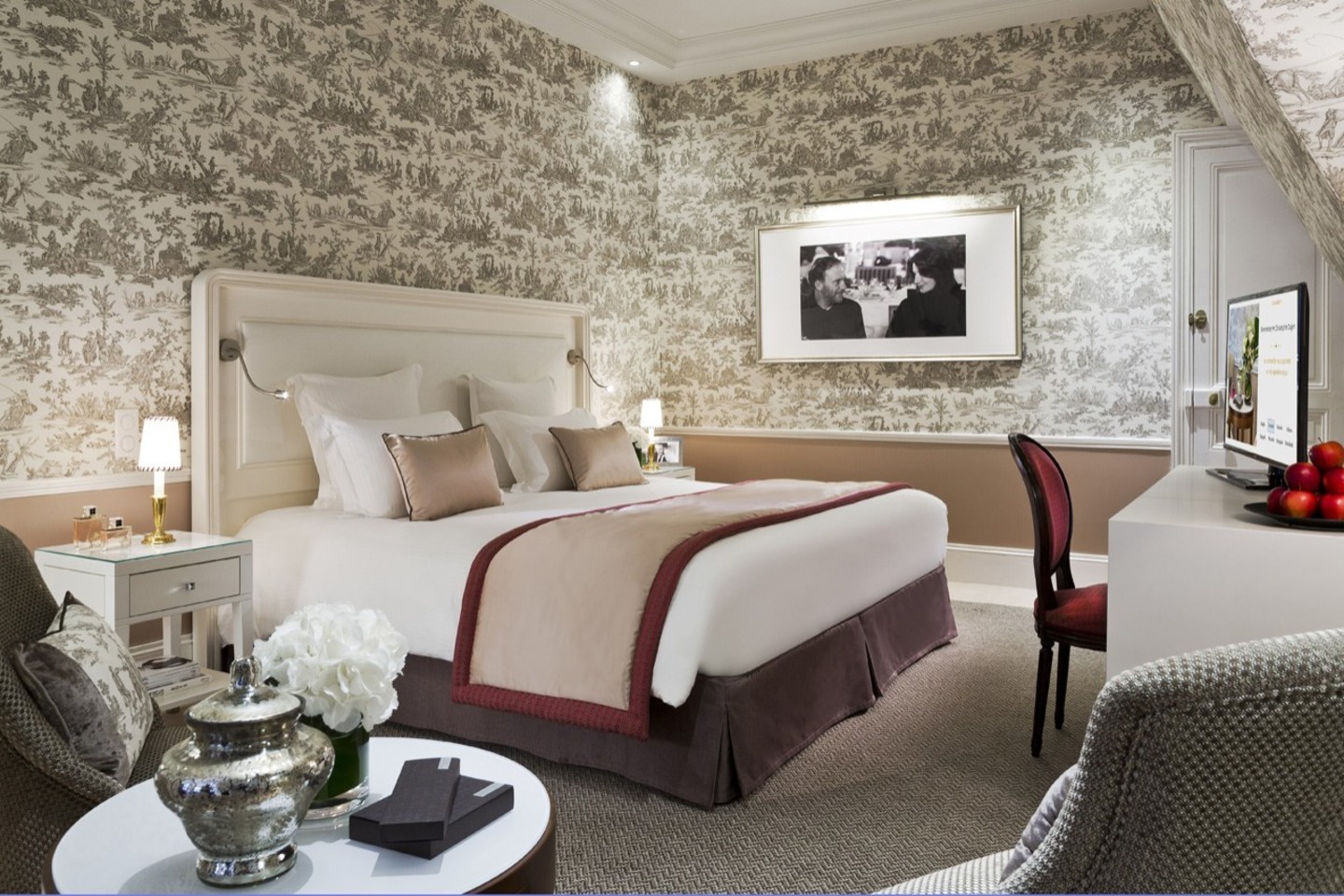 A toile-papered room at Le Normandy in Deauville, the bed dressed in cream and rose