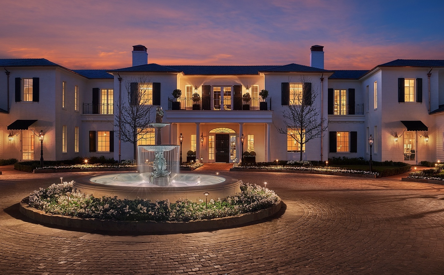 The manor house and lit fountain courtyard at Rosewood Miramar Beach at dusk